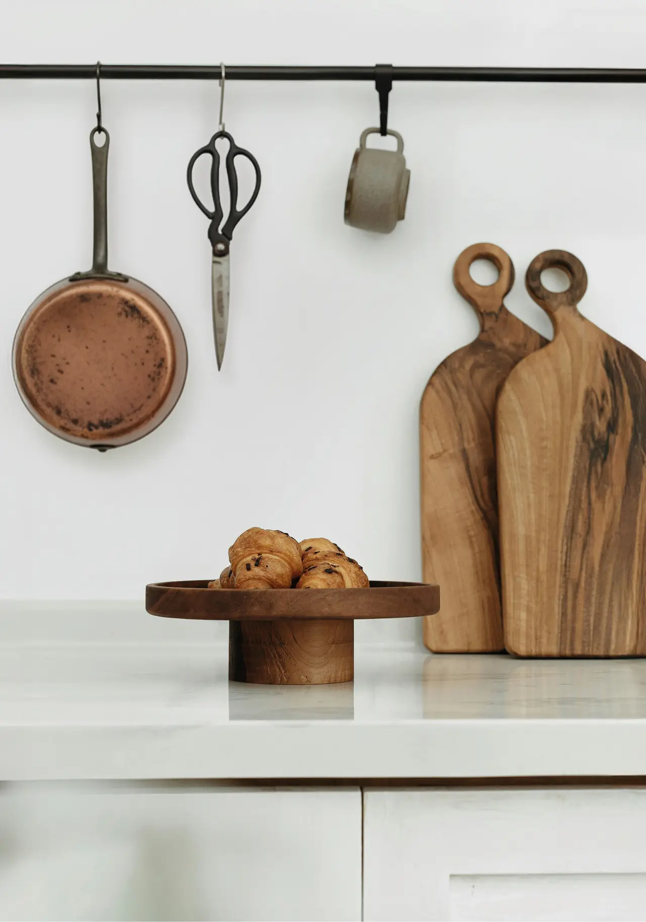 Moderne Küche mit Holzelementen, Kupferpfanne und Schneidebrettern aus Holz, stilvolle Küchendeko im natürlichen skandinavischen Design.